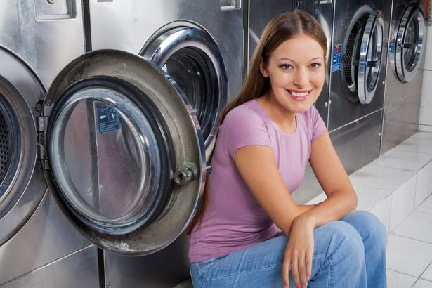 chica sonriente apoyada en lavadora