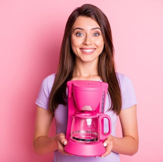 chica sonriente con maquina de cafe rosa